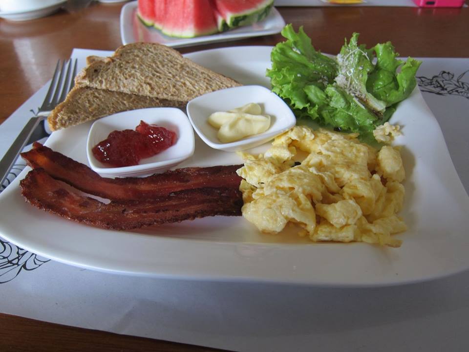 Americano. Slices of toasts with Strawberry jam and fresh butter. Strips of bacon with scrambled eggs.